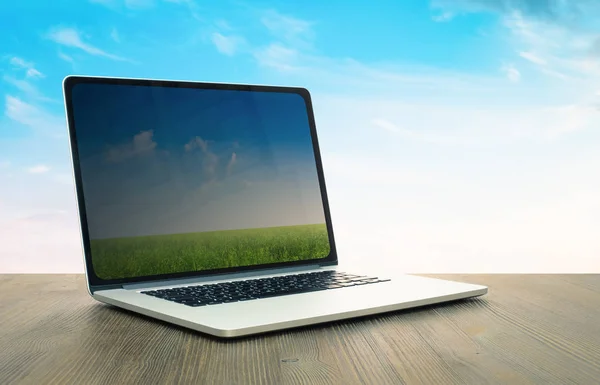 pc on wooden table, sky background