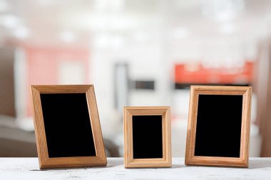 Oturma odasındaki ahşap masada fotoğraf çerçeveleri.