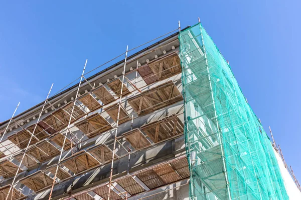 high scaffolding for building facade renovation against blue sky