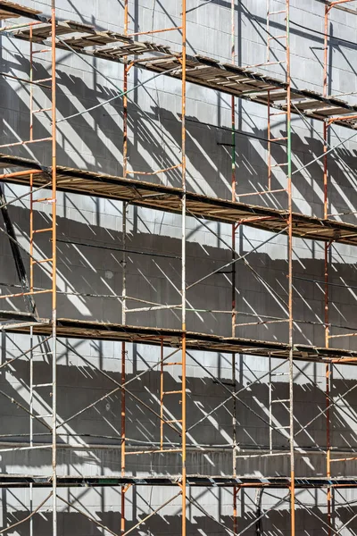 building facade with scaffolding under renovation in sunlight. construction background