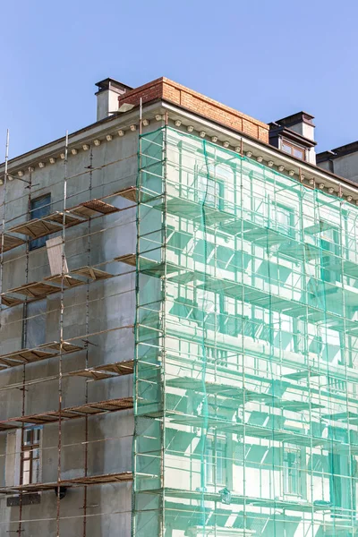 building exterior under renovation with scaffolding and green netting