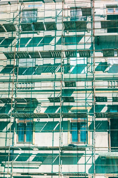reconstruction of city building. metal scaffolding with green protective net near the facade