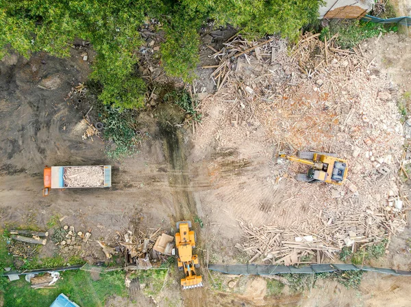 heavy construction machines clearing out pile of debris of destroyed building after house demolition. aerial view