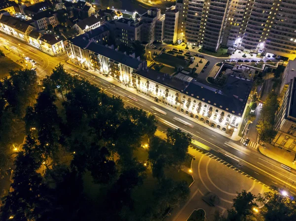 Aerial top view of city street and apartment buildings. City illumination. Night cityscape