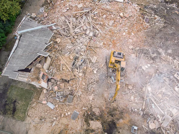 aerial view of demolition site with ruined old building and yellow excavator clearing out redevelopment area