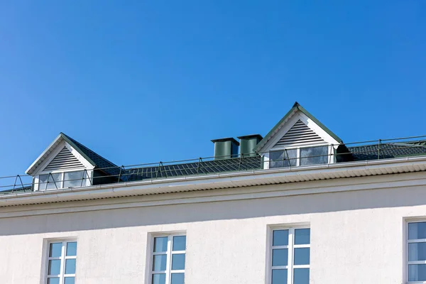 house roof with new rain gutter system against blue sky