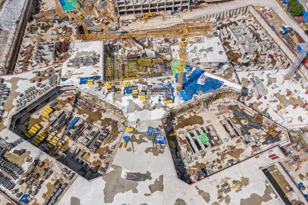 aerial top view of building multi-level foundation in city construction site. high tower cranes and heavy machinery working