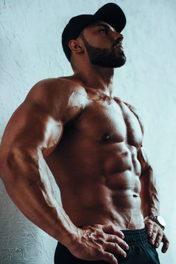 Beyaz duvar arka plan üzerinde şapkalı güçlü delikanlı vücut geliştirmeci