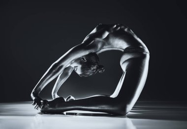 Genç üstsüz kadın esniyor. Metalik deri efekti için gümüş vücut boyası ve tonlama. Dramatik renkler.