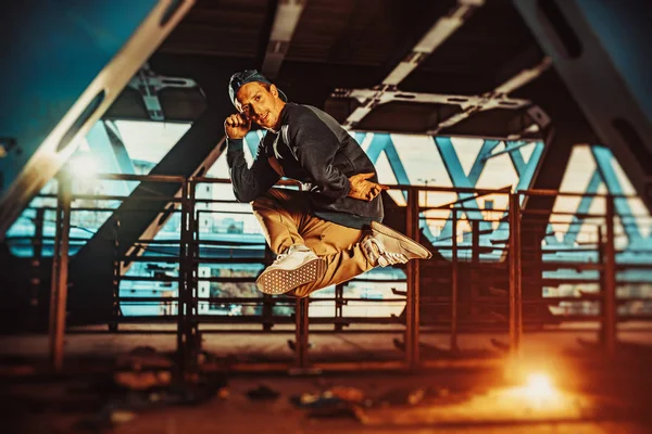 Young cool man break dancer jumping. Urban bridge with cool and warm lights background.