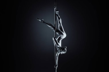 Genç kadın direk dansı. Gümüş renkli vücut boyası ve tonlama. Dramatik renkler.