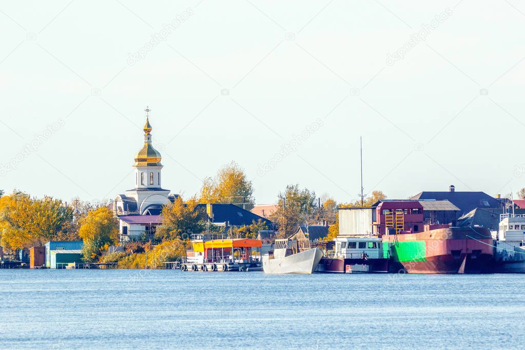 image of the church on the banks of the autumn river at the pier
