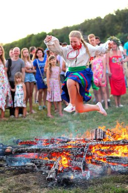 Kiev, Ukrayna - 6 Temmuz 2018: Genç kız Ulusal giyim atlar üzerinde şenlik ateşi Pirogovo açık hava Ukrayna Halk Müzesi Ivana Kupala tatil geleneksel Slav kutlama sırasında alevler içinde