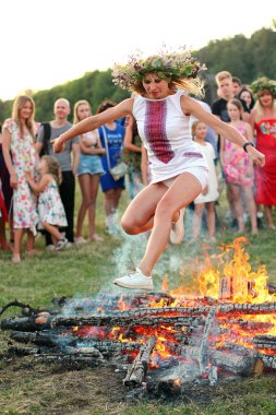 Kiev, Ukrayna - 6 Temmuz 2018: Genç kadın Pirogovo açık hava Ukrayna Halk Müzesi Ivana Kupala tatil geleneksel Slav kutlama sırasında şenlik ateşi alevler üzerinde atlar