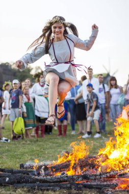 Kiev, Ukrayna - 6 Temmuz 2018: Genç kız Pirogovo açık hava Ukrayna Halk Müzesi Ivana Kupala tatil geleneksel Slav kutlama sırasında şenlik ateşi alevler üzerinde atlar