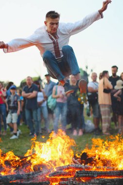 Kiev, Ukrayna - 6 Temmuz 2018: Genç atlar şenlik ateşi alevler içinde Pirogovo açık hava Ukrayna Halk Müzesi Ivana Kupala tatil geleneksel Slav kutlama sırasında adam