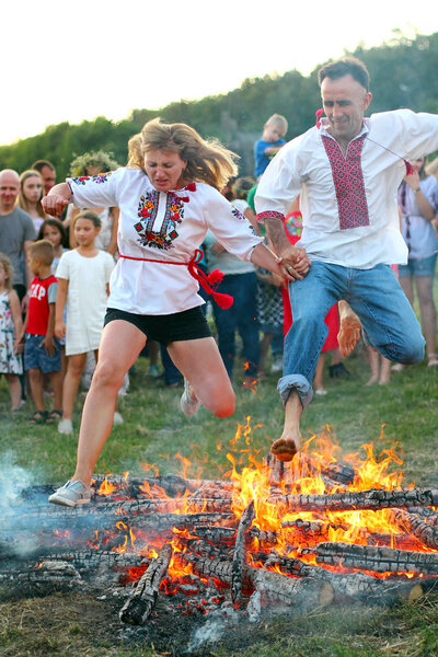 KYIV, UKRAINE - JULY 6, 2018: People jump over the flames of bonfire during the traditional Slavic celebration of Ivana Kupala holiday in Pirogovo open-air ukrainian folk museum