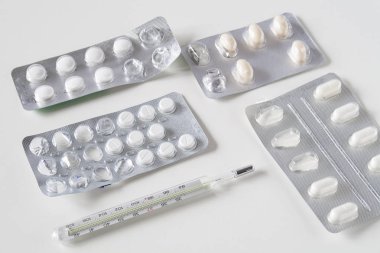 beyaz bir arka plan üzerinde termometre ile haplar