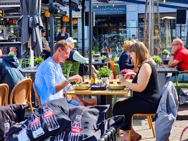 LATVIA, RIGA, SEPTEMBER, 04, 2025: Bir yaz günü insanlar Riga Old Town, Letonya 'daki Livu Meydanı' ndaki açık bir restoranda yemek yerler.