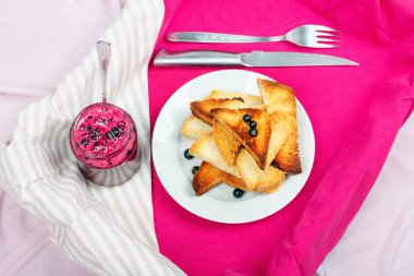 Ev yapımı frenk üzümü reçeli çatal ve bıçak üzerinde parlak koyu kırmızı masa örtüsü ile lezzetli tost ekmeği