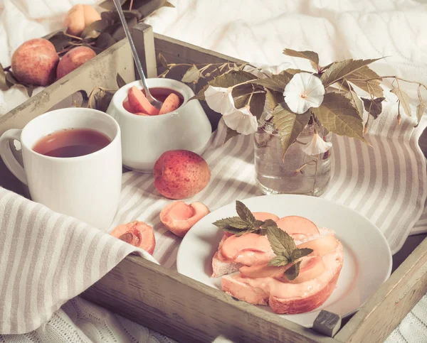 美味的土司面包与自制的杏果酱和杯茶在托盘上 空心菜的花朵背景 — 图库照片