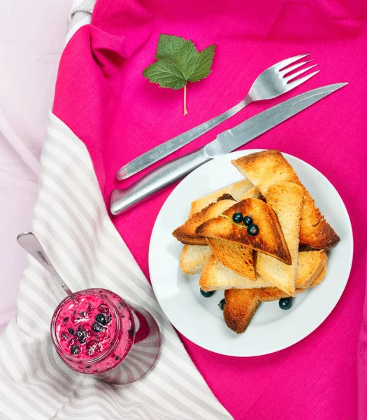 Ev yapımı frenk üzümü reçeli çatal ve bıçak üzerinde parlak koyu kırmızı masa örtüsü ile lezzetli tost ekmeği