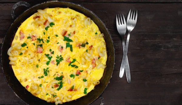 Pastırma, makarna ve yeşillik üzerinde eski siyah kızartma tavası ile geleneksel rustik omlet