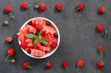 Siyah taş tezgah üzerinde karpuz, ahududu ve Frenk üzümü yeşil nane ile taze sulu adet salata yaprakları