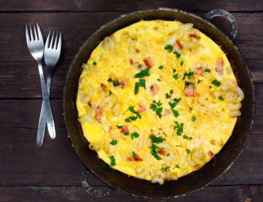 Pastırma, makarna ve yeşillik üzerinde eski siyah kızartma tavası ile geleneksel rustik omlet