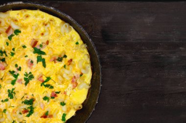 Pastırma, makarna ve Yeşiller eski siyah kızartma tavası vintage ahşap masa arka plan üzerinde tarih ile geleneksel rustik omlet. Kopya girintili