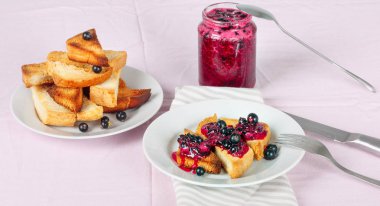 Ev yapımı frenk üzümü reçeli çatal ve bıçak üzerinde parlak koyu kırmızı masa örtüsü ile lezzetli tost ekmeği