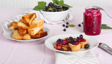 Ev yapımı frenk üzümü reçeli çatal ve bıçak üzerinde parlak koyu kırmızı masa örtüsü ile lezzetli tost ekmeği