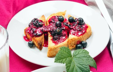 Lezzetli tost ekmeği ev yapımı frenk üzümü reçeli ve süt parlak kırmızı masa aralığında.