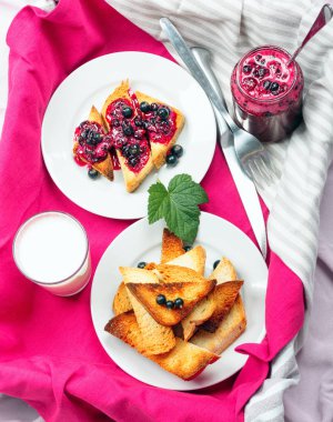 Lezzetli tost ekmeği ev yapımı frenk üzümü reçeli ve süt parlak kırmızı masa aralığında.
