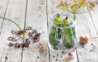Salatalık dereotu ve sarımsaklı ahşap masa üzerinde cam kavanoza korunmuş 