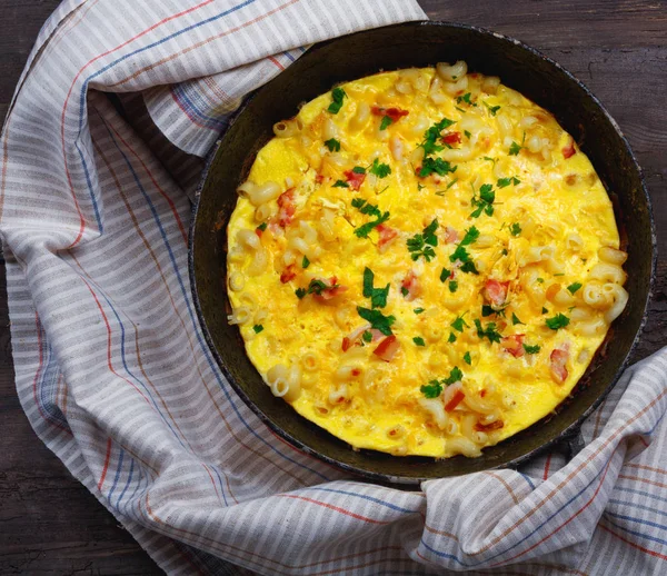 Pastırma, makarna ve Yeşiller eski siyah kızartma tavası vintage ahşap masa arka plan üzerinde tarih ile geleneksel rustik omlet. Kopya alanı