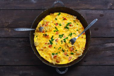 Pastırma, makarna ve yeşillik üzerinde eski siyah kızartma tavası ile geleneksel rustik omlet