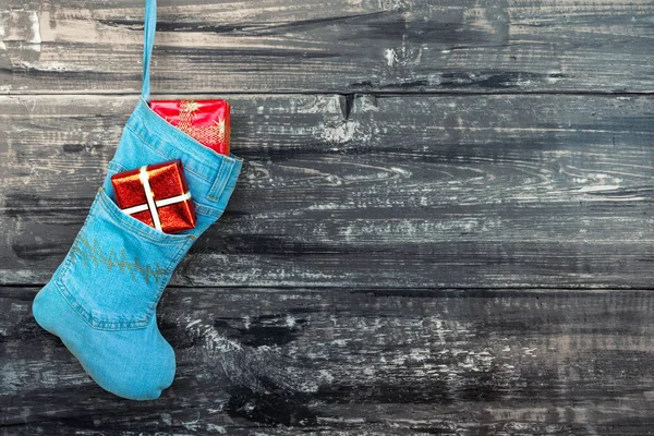 Blue denim christmas boot with gifts on background wooden wall