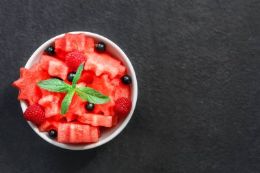 Siyah taş tezgah üzerinde karpuz, ahududu ve Frenk üzümü yeşil nane ile taze sulu adet salata yaprakları
