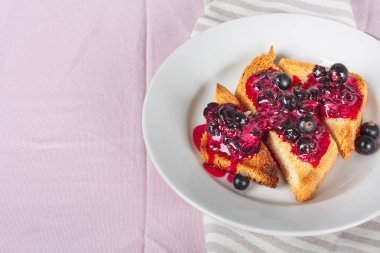 Ev yapımı frenk üzümü reçeli çatal ve bıçak üzerinde parlak koyu kırmızı masa örtüsü ile lezzetli tost ekmeği