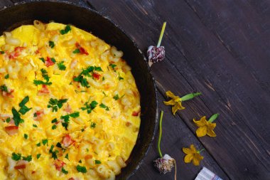 Pastırma, makarna ve Yeşiller eski siyah kızartma tavası vintage ahşap masa arka plan üzerinde tarih ile geleneksel rustik omlet. Kopya alanı