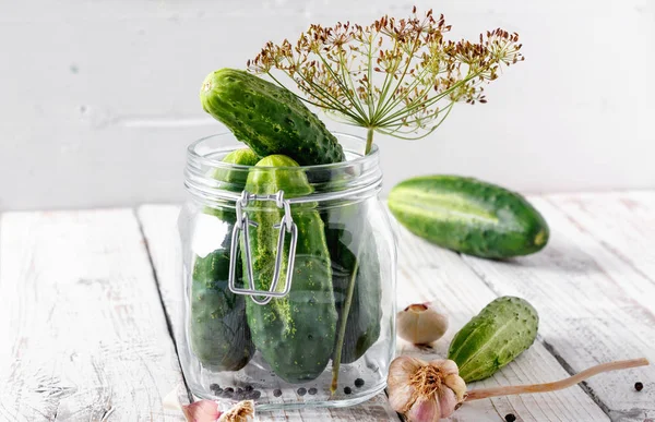 Preserved cucumbers in glass jar with dill and garlic on wooden table