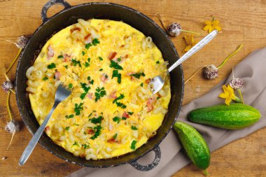 Pastırma, makarna ve Yeşiller eski siyah kızartma tavası vintage ahşap masa arka plan üzerinde tarih ile geleneksel rustik omlet. Kopya alanı