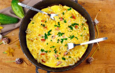 Pastırma, makarna ve Yeşiller eski siyah kızartma tavası vintage ahşap masa arka plan üzerinde tarih ile geleneksel rustik omlet. Kopya alanı