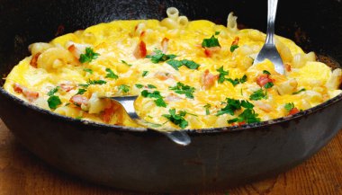Pastırma, makarna ve yeşillik üzerinde eski siyah kızartma tavası ile geleneksel rustik omlet