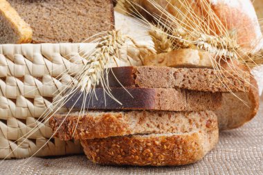 Ahşap masa üzerinde hasır sepet içinde kaba taşlama, çavdar ve buğday unu ekmek