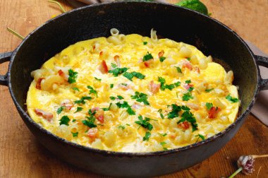 Pastırma, makarna ve Yeşiller eski siyah kızartma tavası vintage ahşap masa arka plan üzerinde tarih ile geleneksel rustik omlet. Kopya alanı