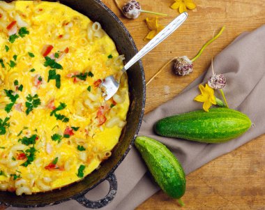 Pastırma, makarna ve Yeşiller eski siyah kızartma tavası vintage ahşap masa arka plan üzerinde tarih ile geleneksel rustik omlet. Kopya alanı