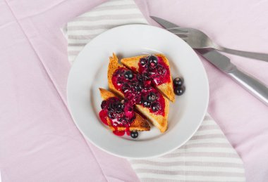 Ev yapımı frenk üzümü reçeli çatal ve bıçak üzerinde parlak koyu kırmızı masa örtüsü ile lezzetli tost ekmeği