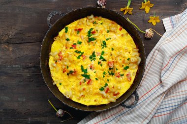 Pastırma, makarna ve Yeşiller eski siyah kızartma tavası vintage ahşap masa arka plan üzerinde tarih ile geleneksel rustik omlet. Kopya alanı